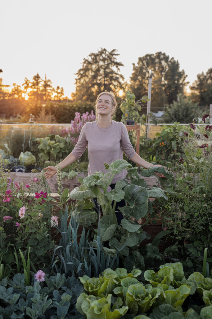 A woman celebrating her thriving garden, showcasing a sense of accomplishment and satisfaction achieved through gardening