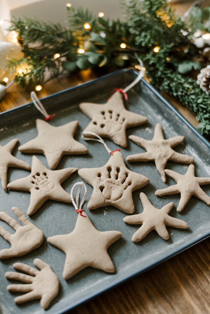 Salt dough ornaments in star and heart shapes, featuring painted handprints, arranged on a tray.