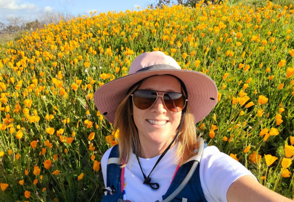 Kellie from Bloom with Kellie in a field of flower blooms on a hike